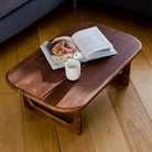 Wooden coffee table with a magazine and cup on a wooden floor