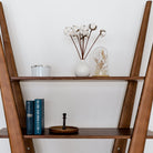 Wooden ladder shelf with decorative items against a white wall